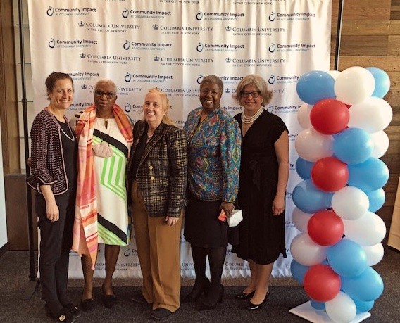 2022 Gala image of people smiling in front of the Community Impact logo backdrop at Chelsea Piers